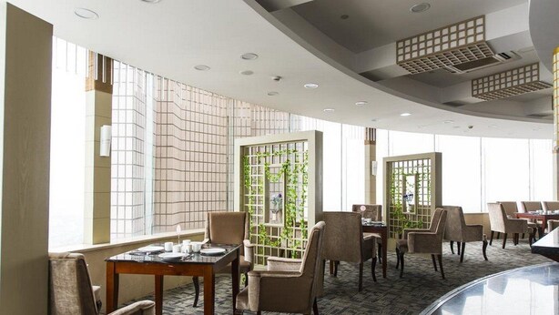 A modern restaurant with a curved ceiling, large windows, and a mix of wooden and upholstered chairs. - JI Hotel Shanghai Chuansha Branch (Shanghai)