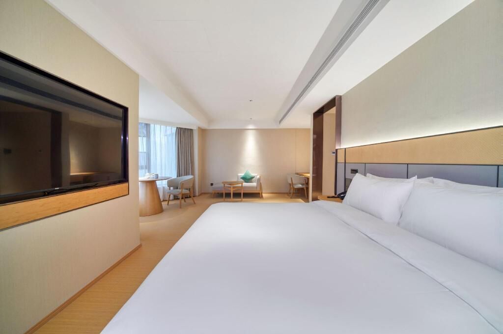 A hotel room with a large bed, a desk, a chair, and a TV.