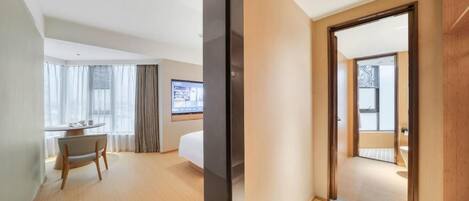A hotel room with a bed, a desk, a chair, and a TV. There is a sliding door leading to a bathroom.