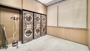 A laundry room with four stacked washing machines and a vacuum cleaner. - JI Hotel Shanghai Chuansha Branch (Shanghai)