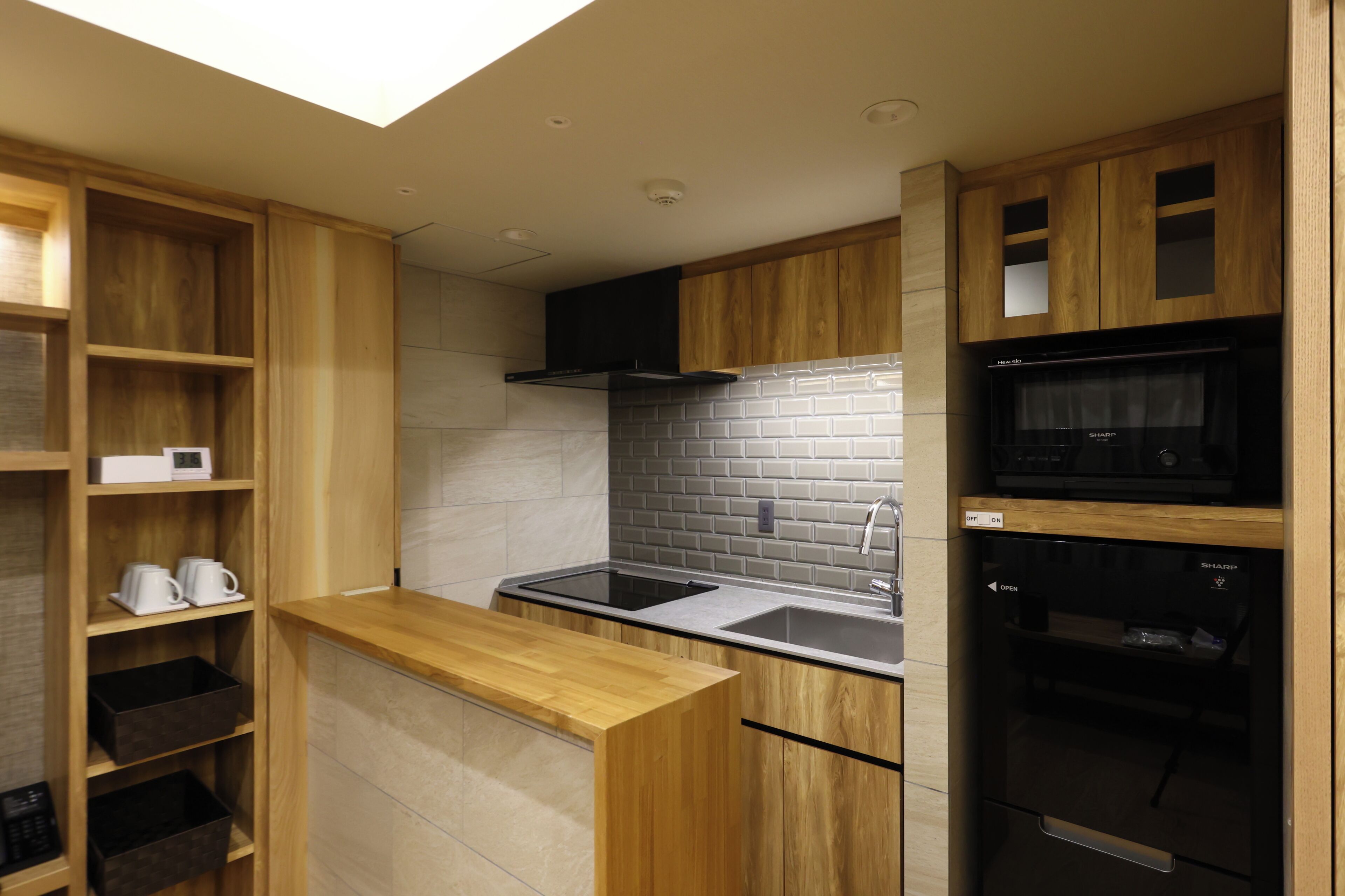 Cocina compacta con armarios de madera, microondas integrado y lavavajillas.