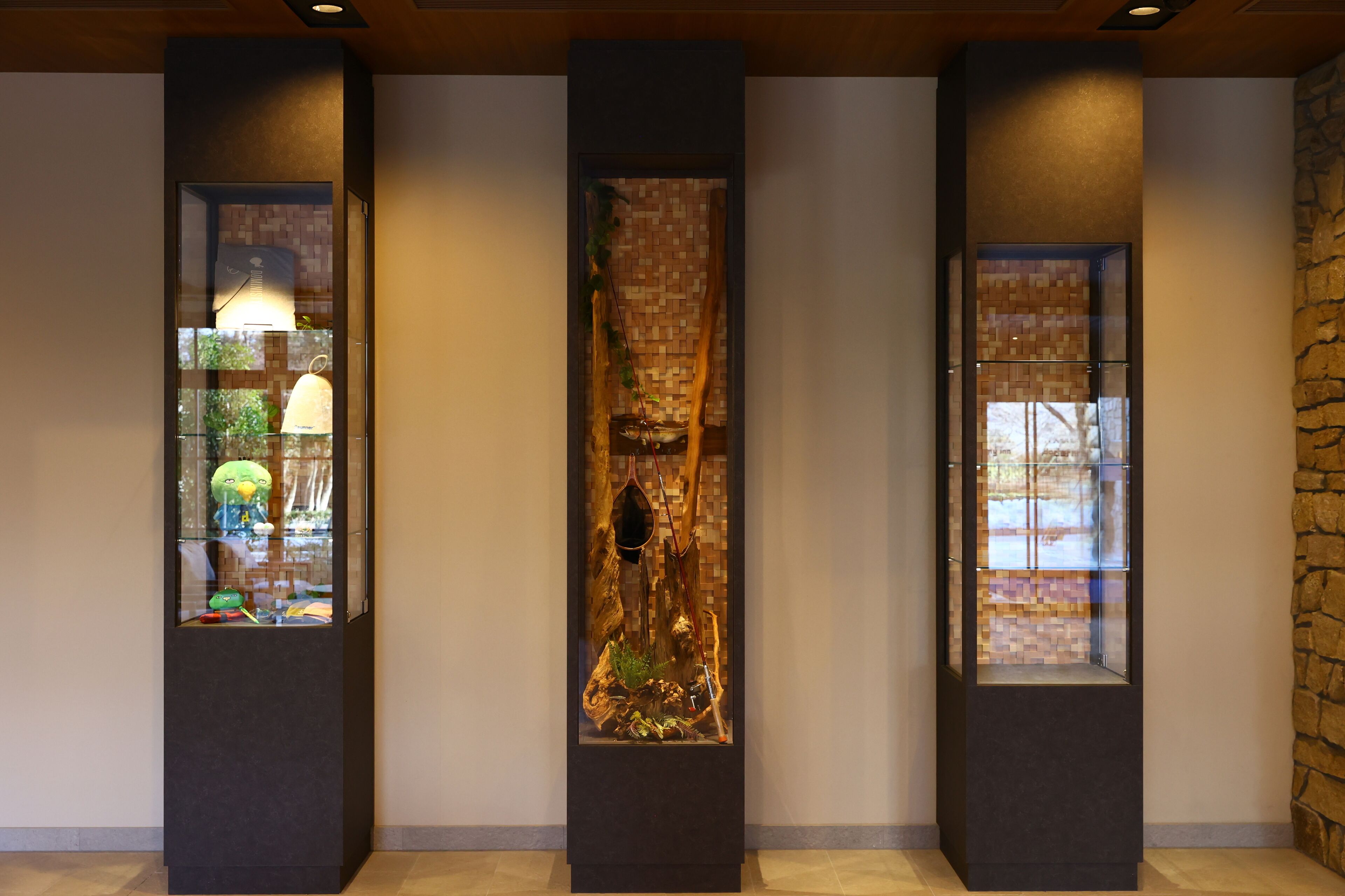 Three vertical display cases with glass fronts, each containing different decorative items.