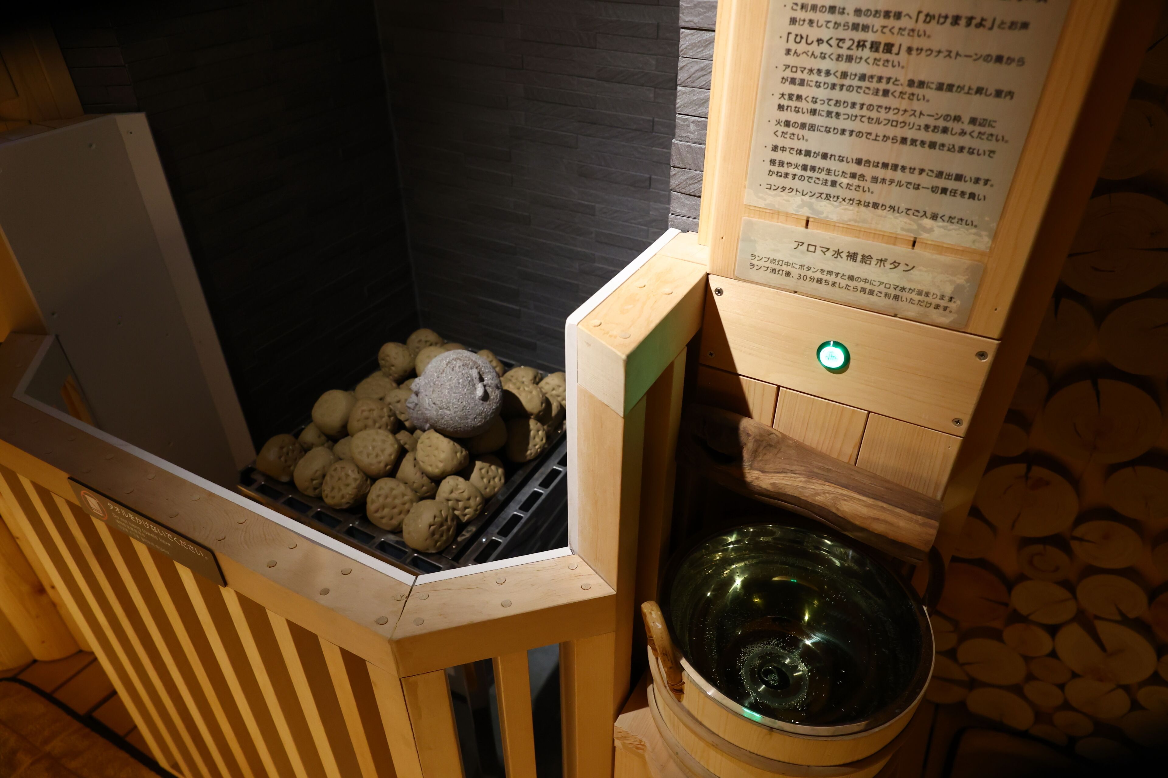 A sauna with a wooden bench, a stone wall, and a sign with Japanese text.