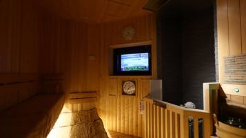 Una sauna de madera con televisión, relojes y una bañera de sauna.