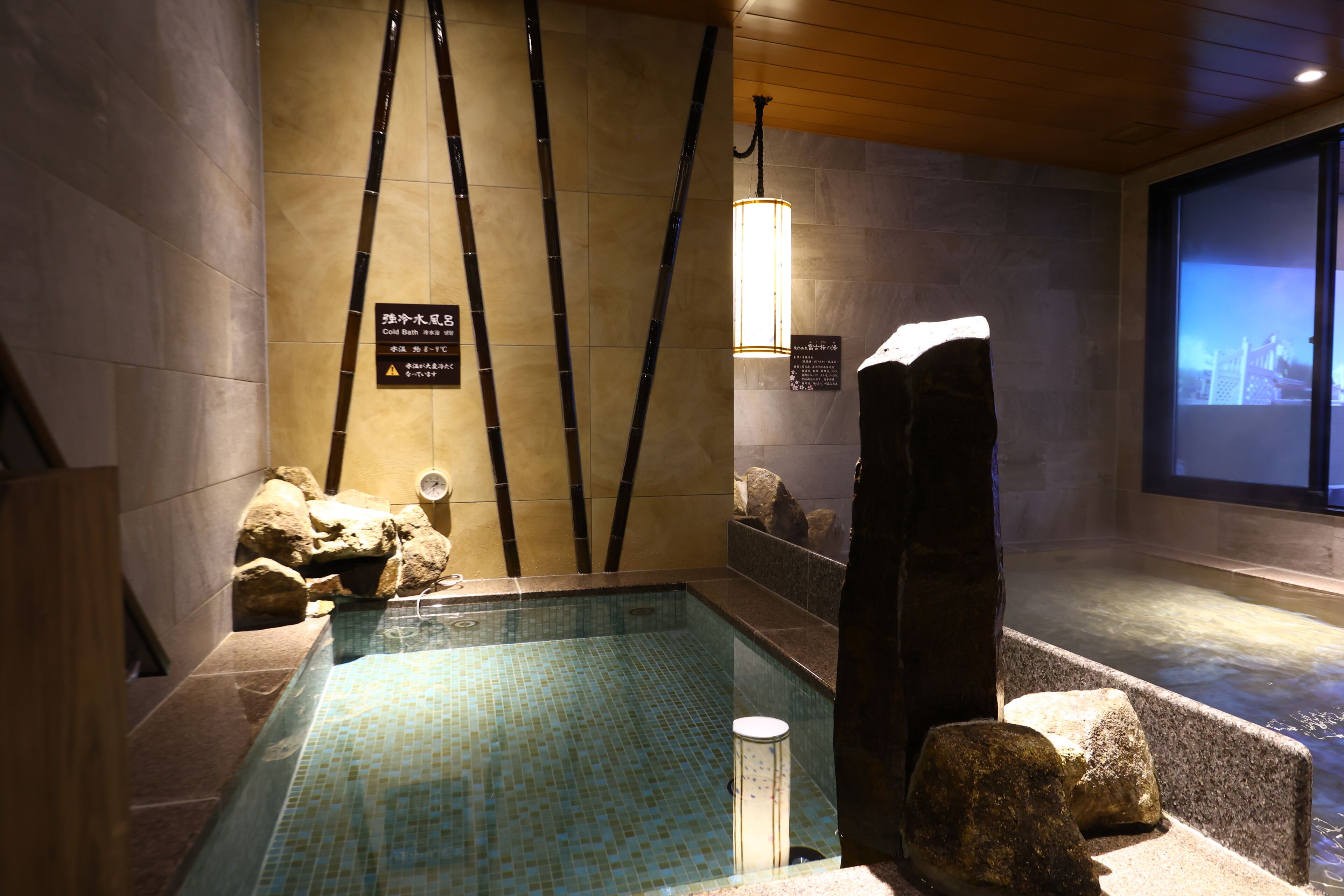 A spa area with a tiled pool, wooden accents, and a stone wall with a sign.