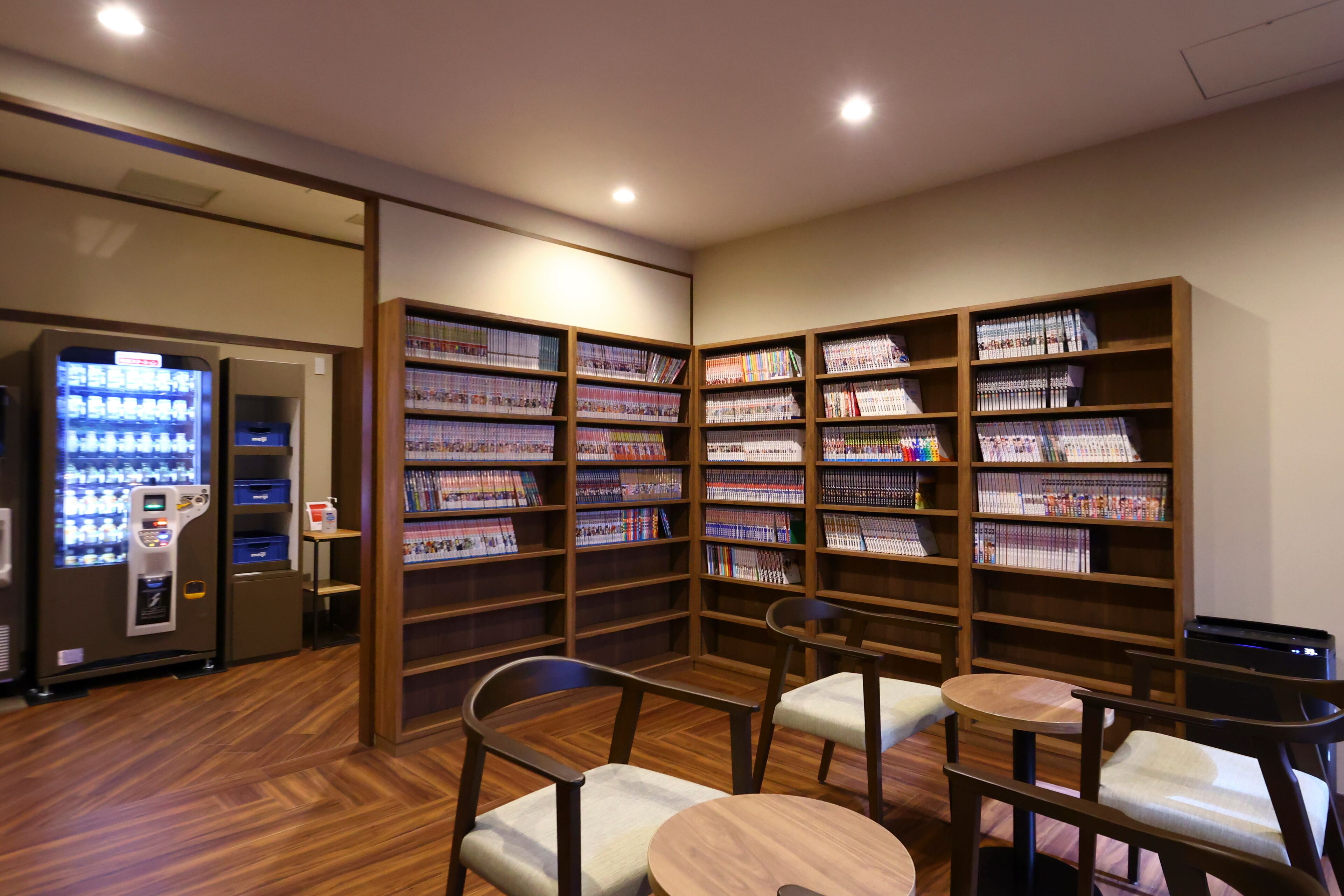 A library with wooden bookshelves, seating areas, and a vending machine.