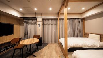 Une chambre d’hôtel avec un plancher en bois, un lit, un bureau avec une chaise, une télévision et des rideaux.