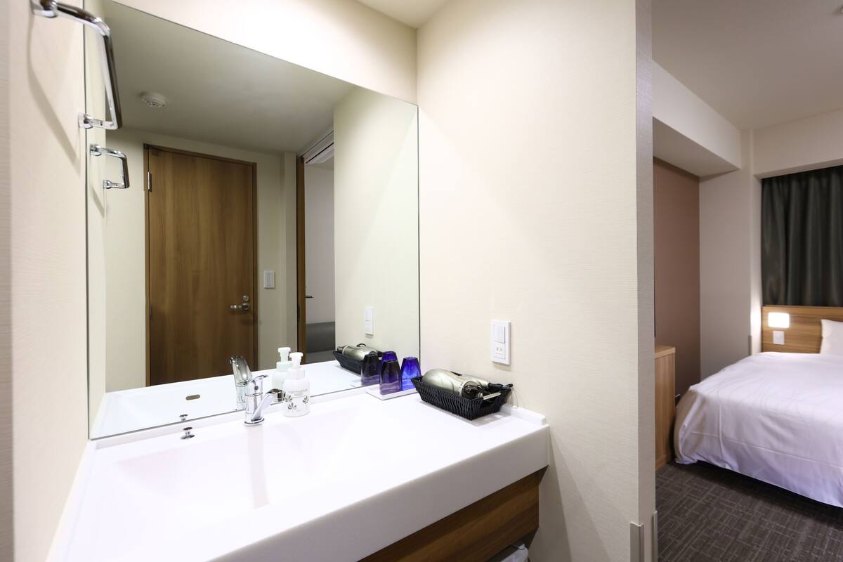 A hotel bathroom with a white sink, a large mirror, and toiletries.