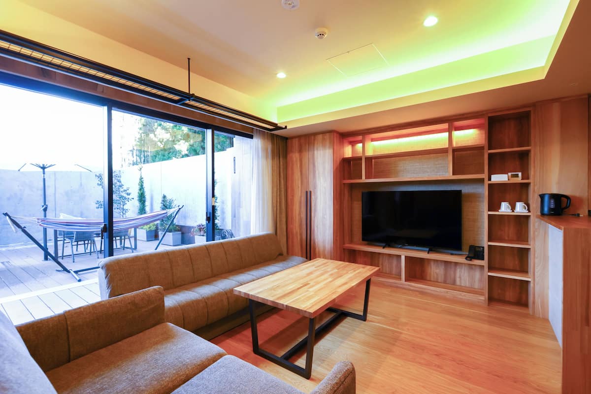 A modern living room with a sofa, a wooden coffee table, a TV, and built-in shelving.