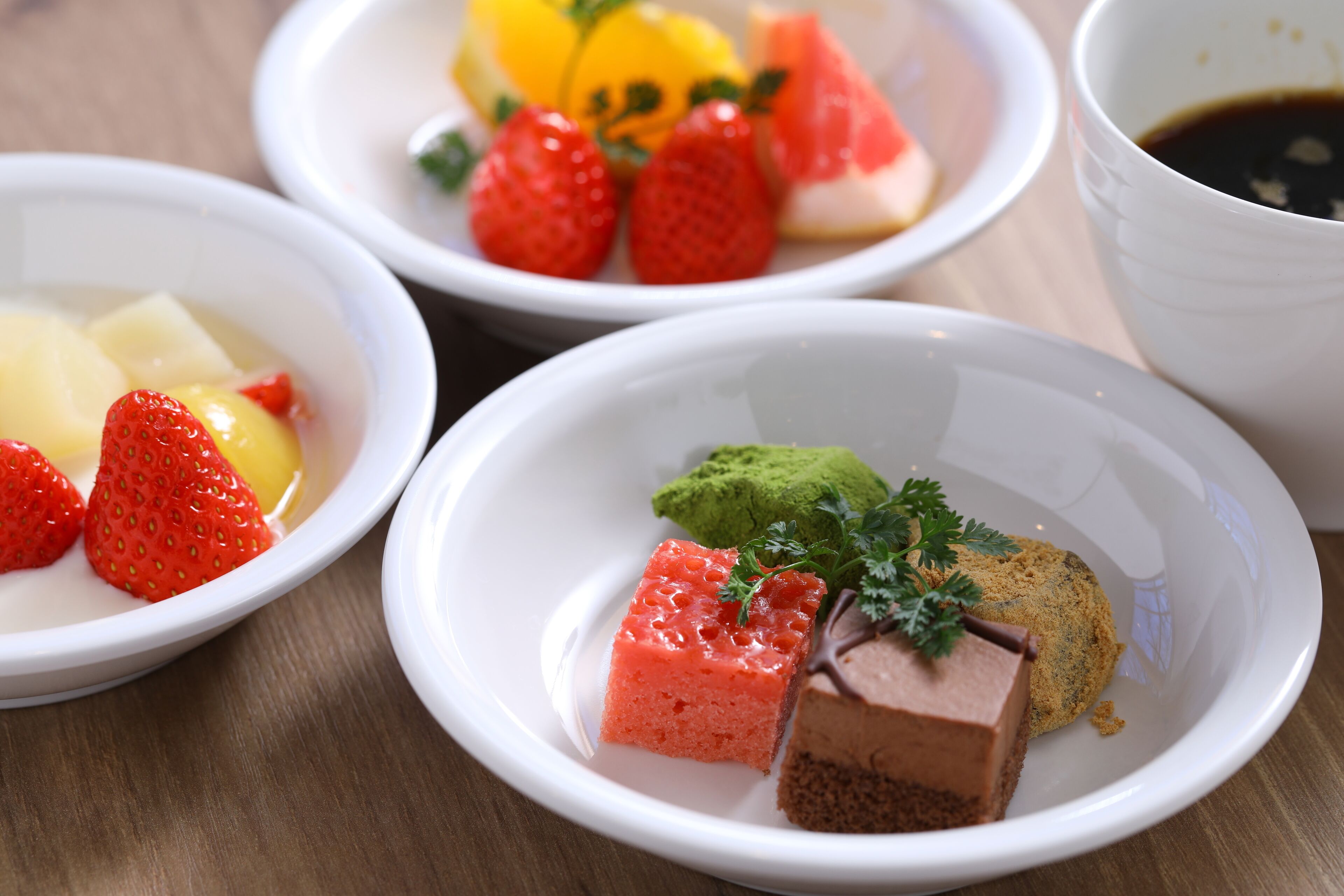 Cuatro tazones blancos con diferentes alimentos, como fresas, pasta verde y chocolate.