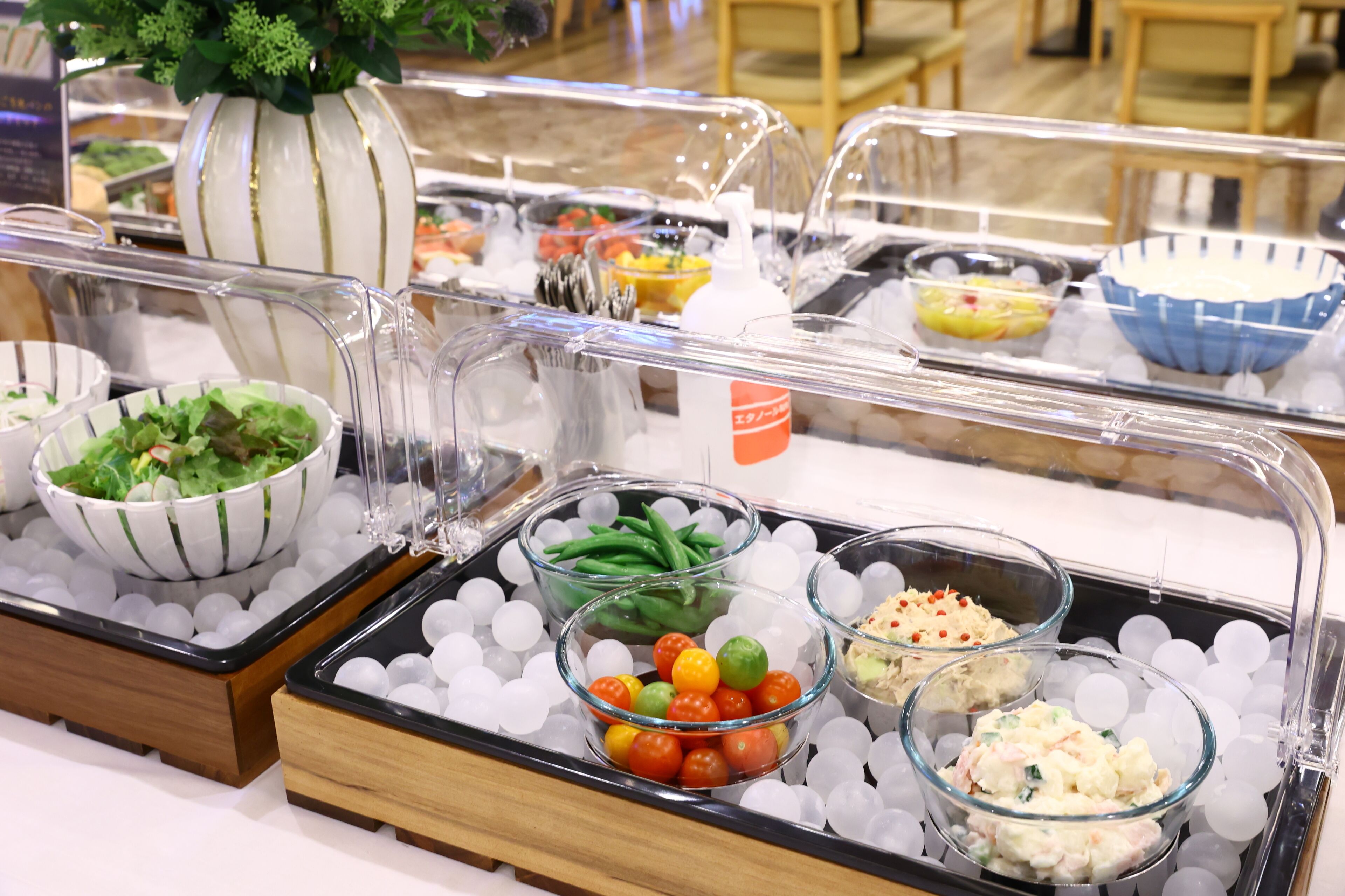 A buffet with various food items in bowls and containers, surrounded by ice cubes.