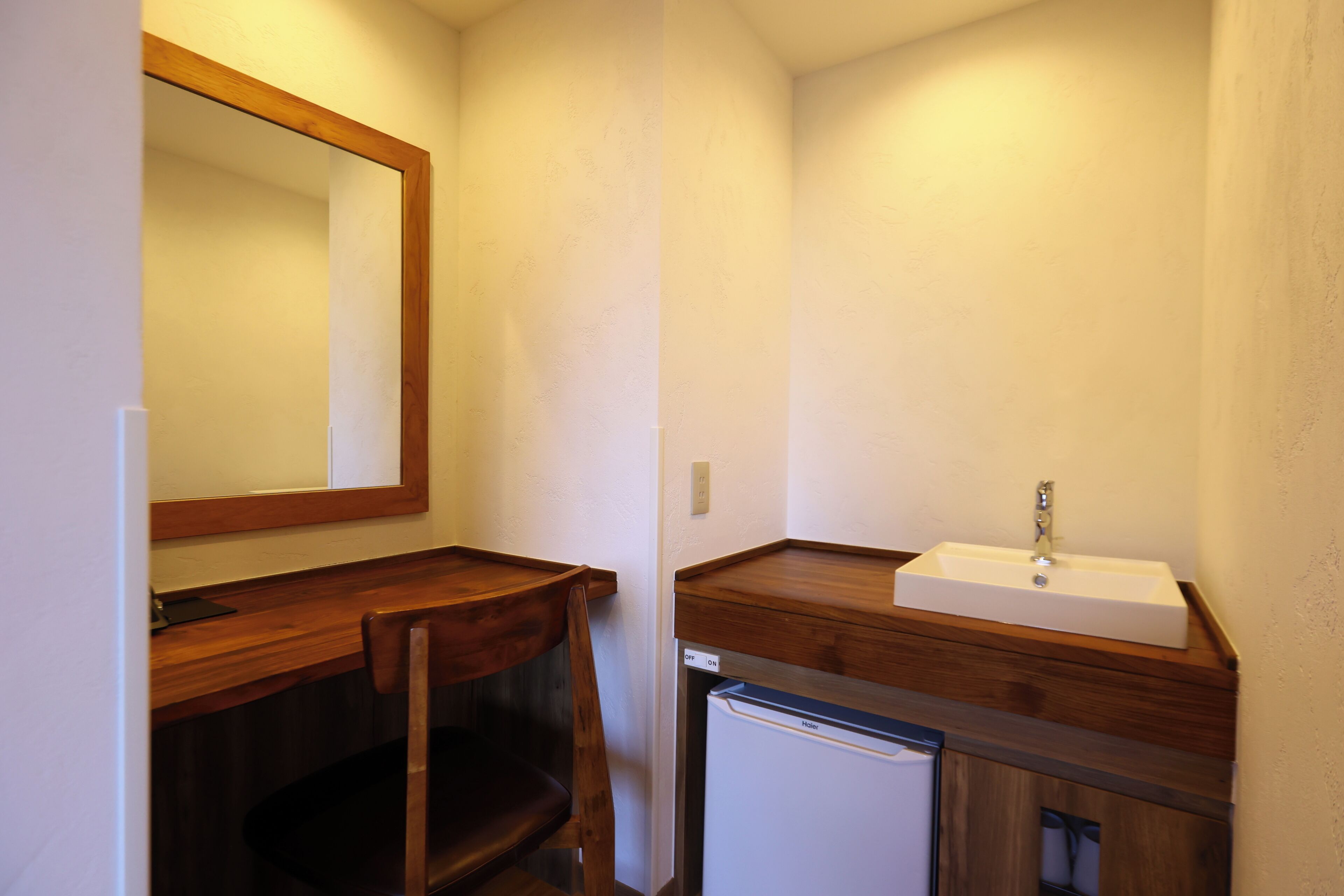 Un bagno compatto con un mobile lavabo in legno, uno specchio, un lavabo e un piccolo frigorifero.