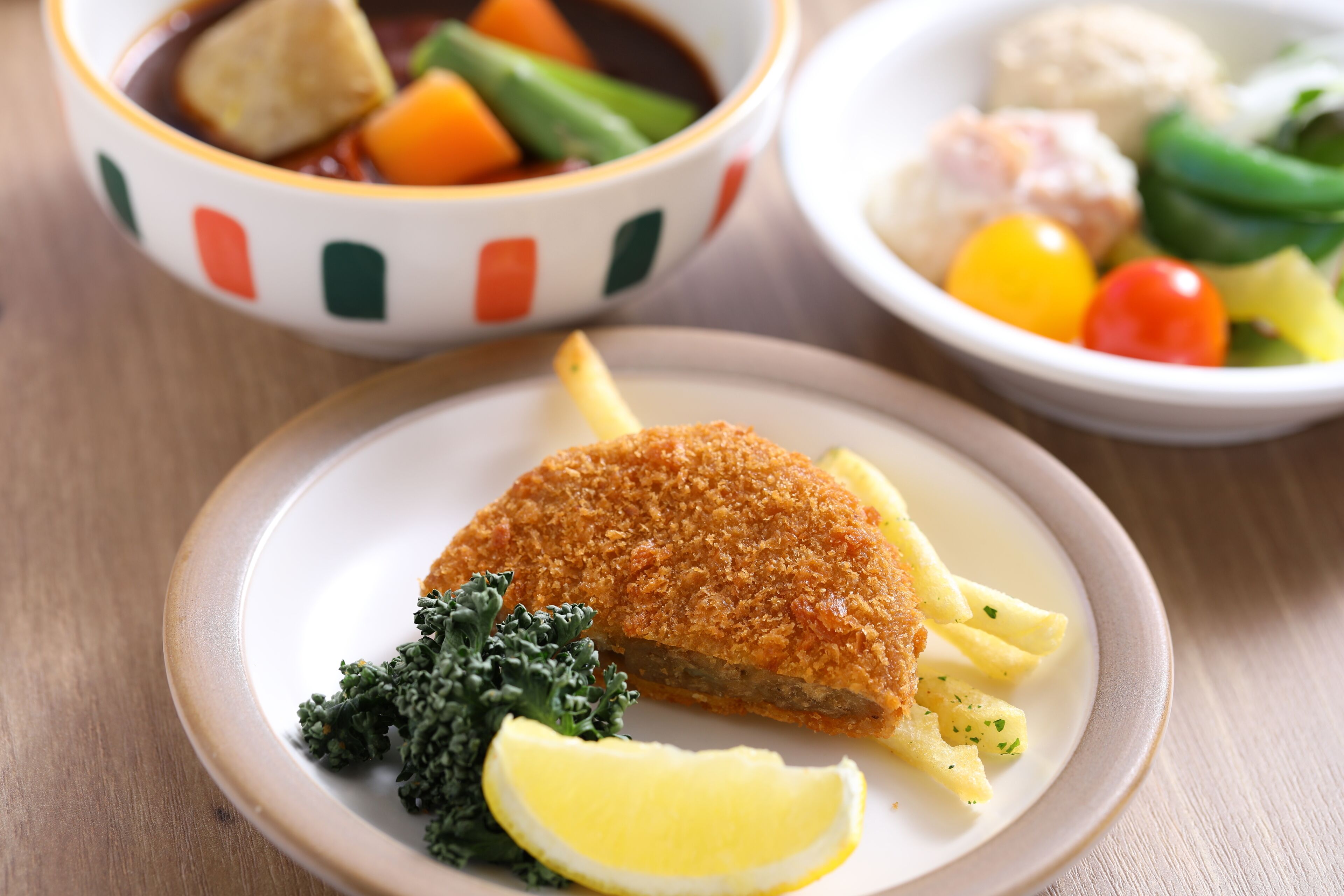 A plate with breaded fish, lemon, and kale.