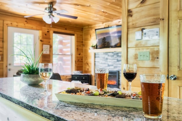 L’intérieur d’un chalet en bois comprend un coin repas doté d’un comptoir en granit, d’une cheminée, ainsi qu’une variété de collations et de boissons.