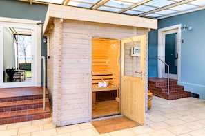 Uma sauna com exterior de madeira, uma porta e uma pequena prateleira interna.