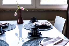 A dining table set with plates, cutlery, and a vase with flowers.