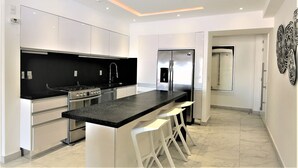 Una cocina moderna con una isla central, electrodomésticos de acero inoxidable y armarios blancos.