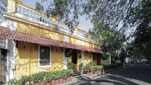 A yellow building with a red roof, a sign reading "Duke's Guest House," and a row of potted plants along the sidewalk. - Dumas Guest House (Puducherry)