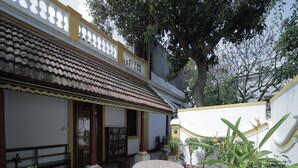 A courtyard with a tiled roof, a round table, and potted plants. - Dumas Guest House (Puducherry)