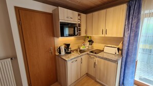 A compact kitchen with wooden cabinets, a microwave, a coffee maker, and a toaster. - Vacation apartment Untersberg up to 2 pers., 34 m², with terrace (Bischofswiesen)