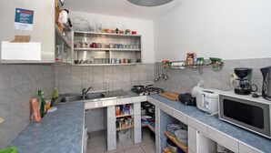 Ett kompakt kök med diskho, spis, mikrovågsugn och diverse köksredskap.