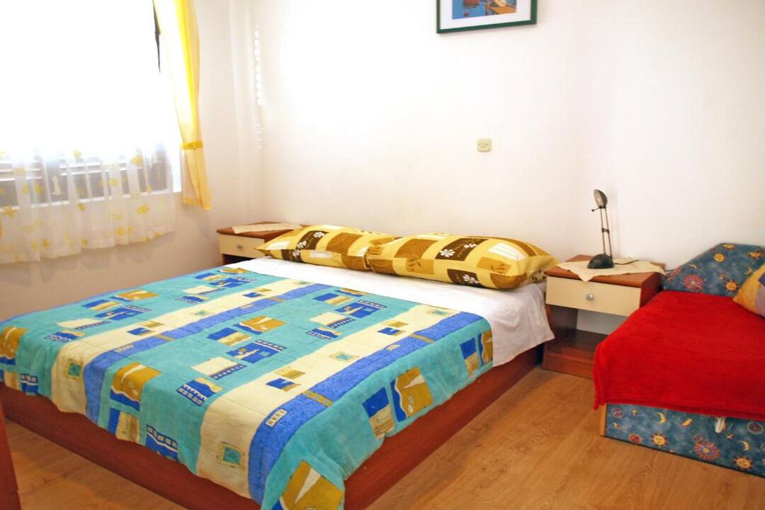 A bedroom with a bed, a nightstand, and a chair.