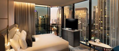 A modern hotel room with a large bed, a TV, and a city view.