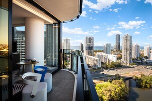 A balcony with a city view, a table with chairs, and a small table with decorative items.