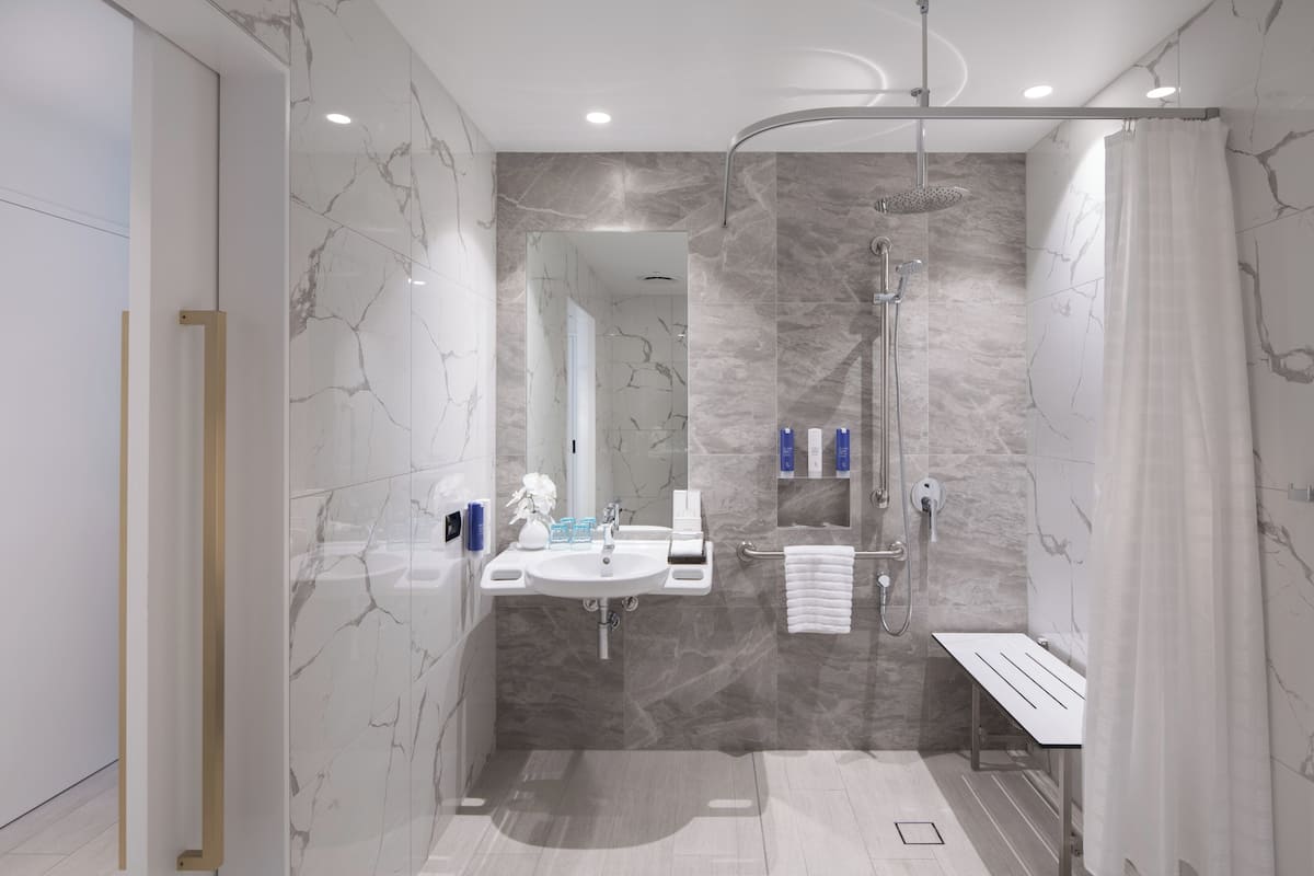 A modern bathroom with a shower, sink, and mirror.