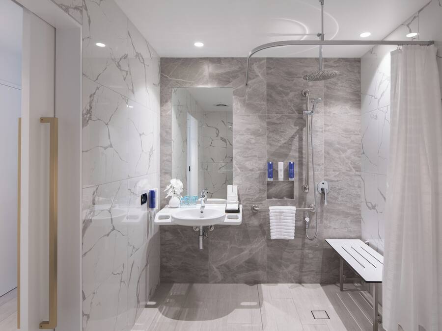 A modern bathroom with a shower, sink, and mirror.