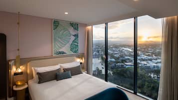 Una habitación de hotel moderna con una cama grande, vistas a la ciudad y un ventanal amplio.