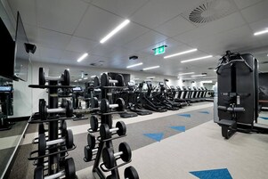 A gym with various exercise equipment, including treadmills and weight machines, arranged in rows.