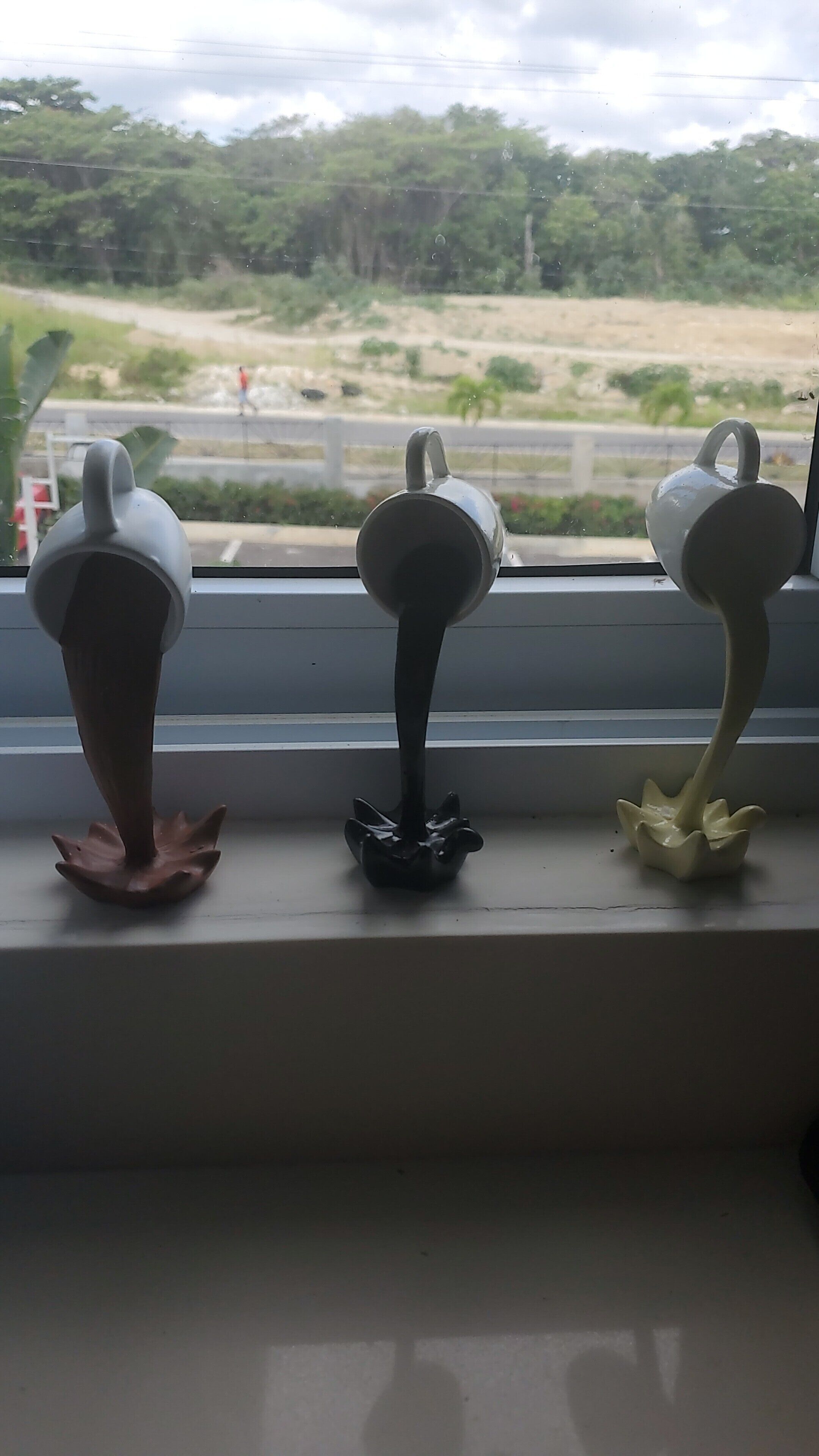Tres jarrones de cerámica con forma de flor en un alféizar.