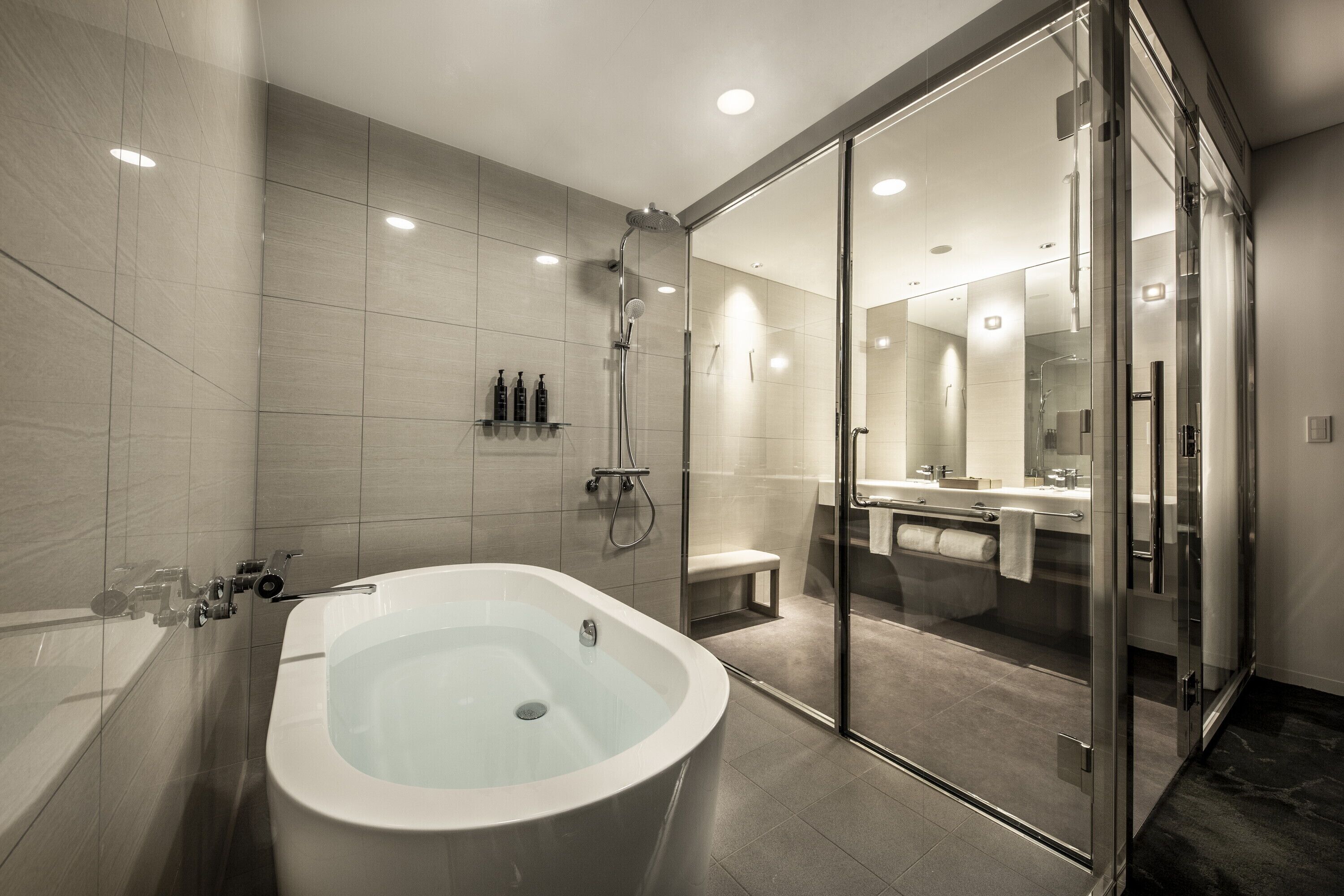 A modern bathroom with a freestanding bathtub, a glass-enclosed shower area, and a vanity with a mirror.