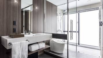 A modern bathroom with a large mirror, a wooden vanity, a glass shower enclosure, and a toilet.