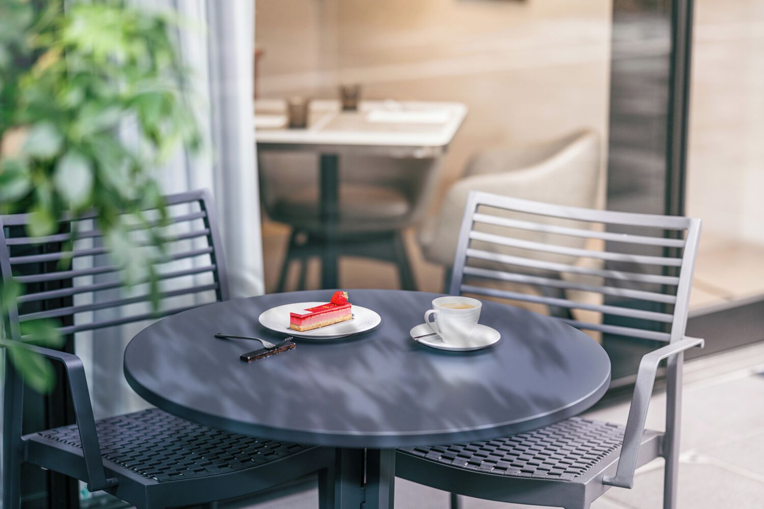 A round table with a slice of red cake and a cup of coffee on a plate.