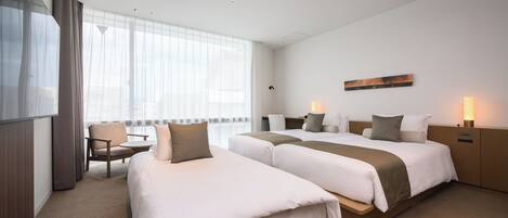 A hotel room with two beds, a desk, and a chair.