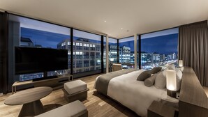 A modern hotel room with a large bed, a flat-screen TV, a dining area, and a city view. - The Royal Park Hotel Iconic Kyoto (Kyoto)