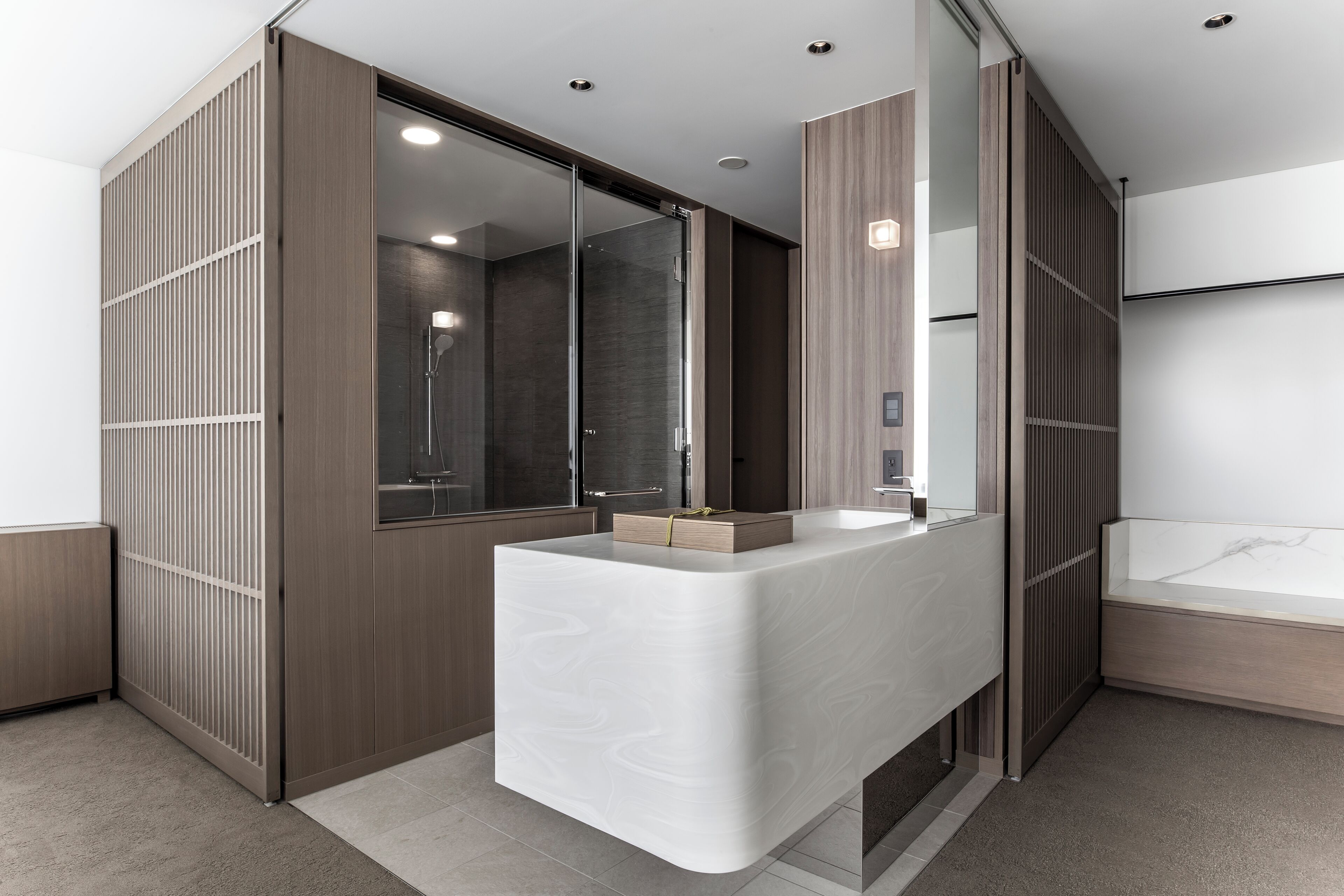 A modern bathroom with a large mirror, a wooden partition, and a built-in sink.