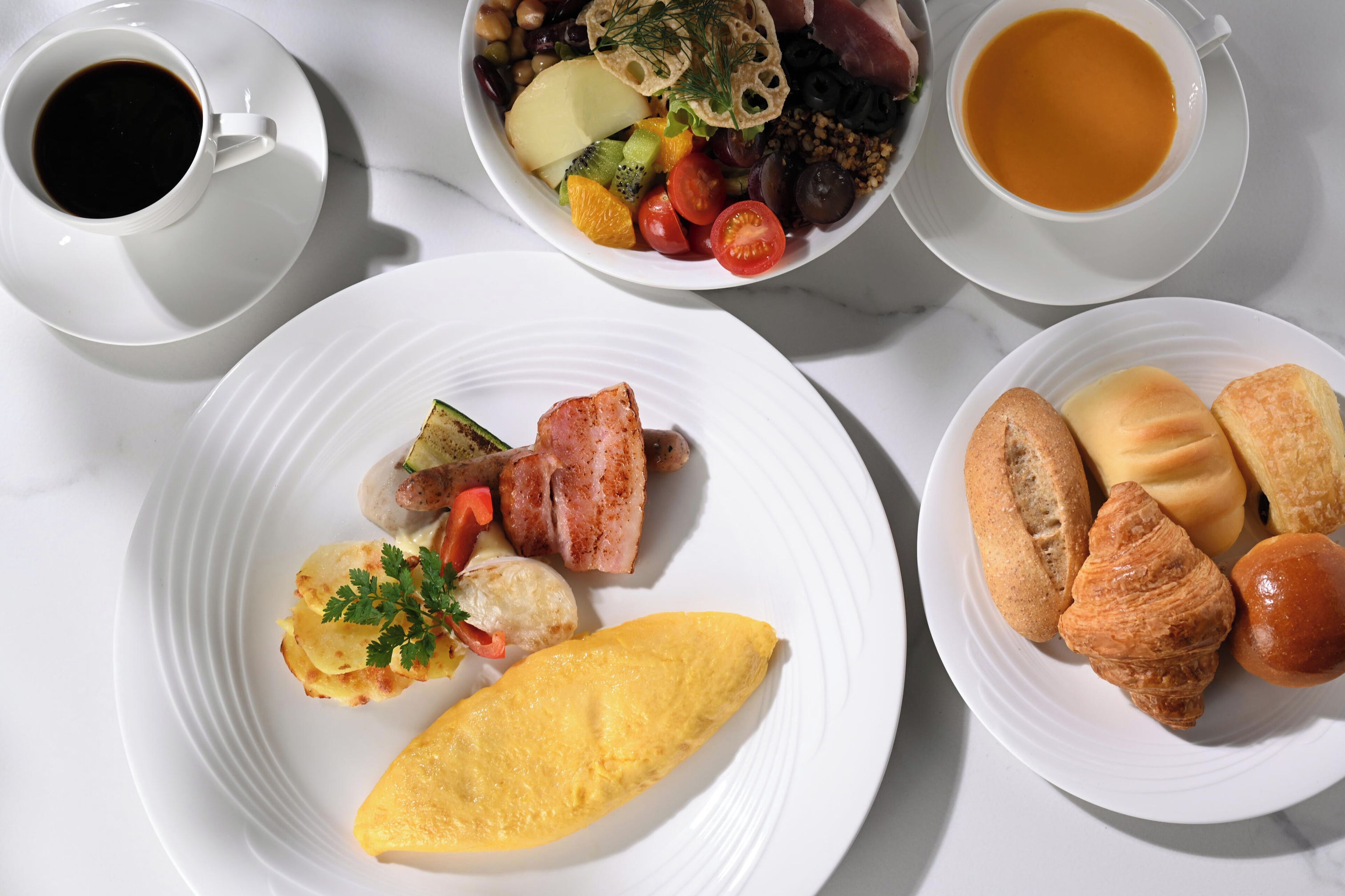 A breakfast setting with plates of food, a cup of coffee, and a cup of tea.
