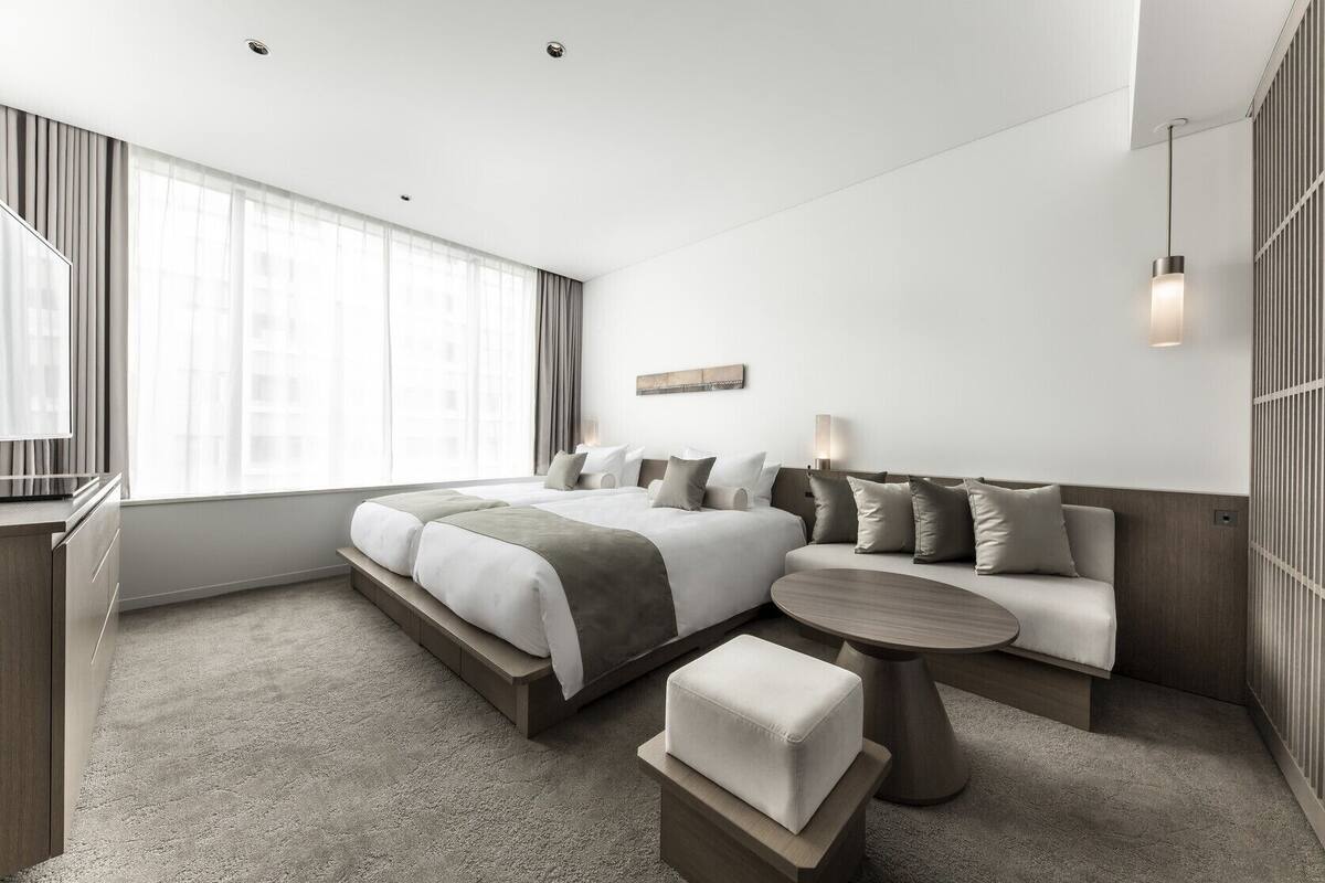 A modern hotel room with a large bed, a sofa, a small table, and a TV.