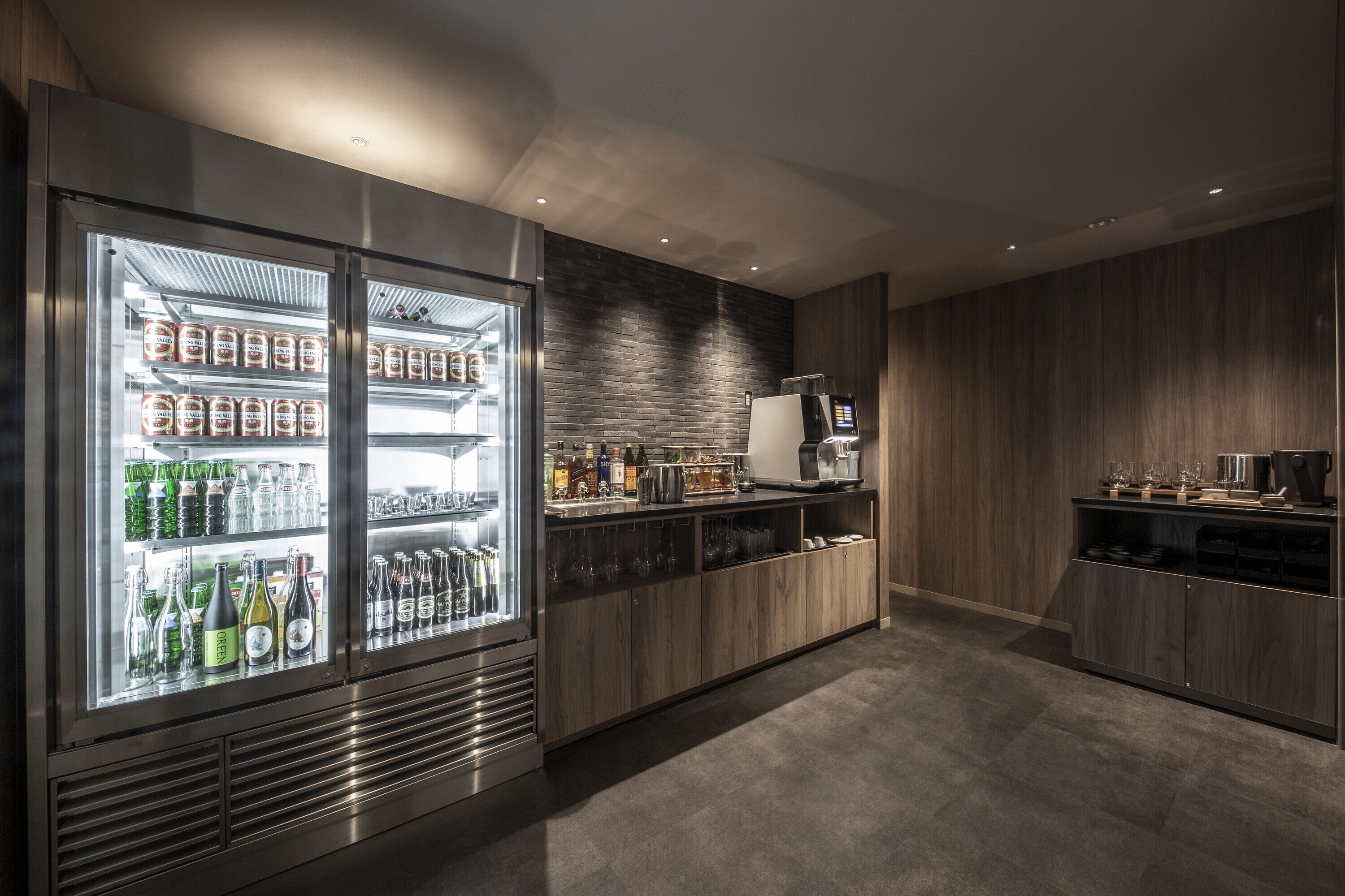 A modern kitchen with a built-in refrigerator stocked with beverages, a coffee machine, and a microwave.