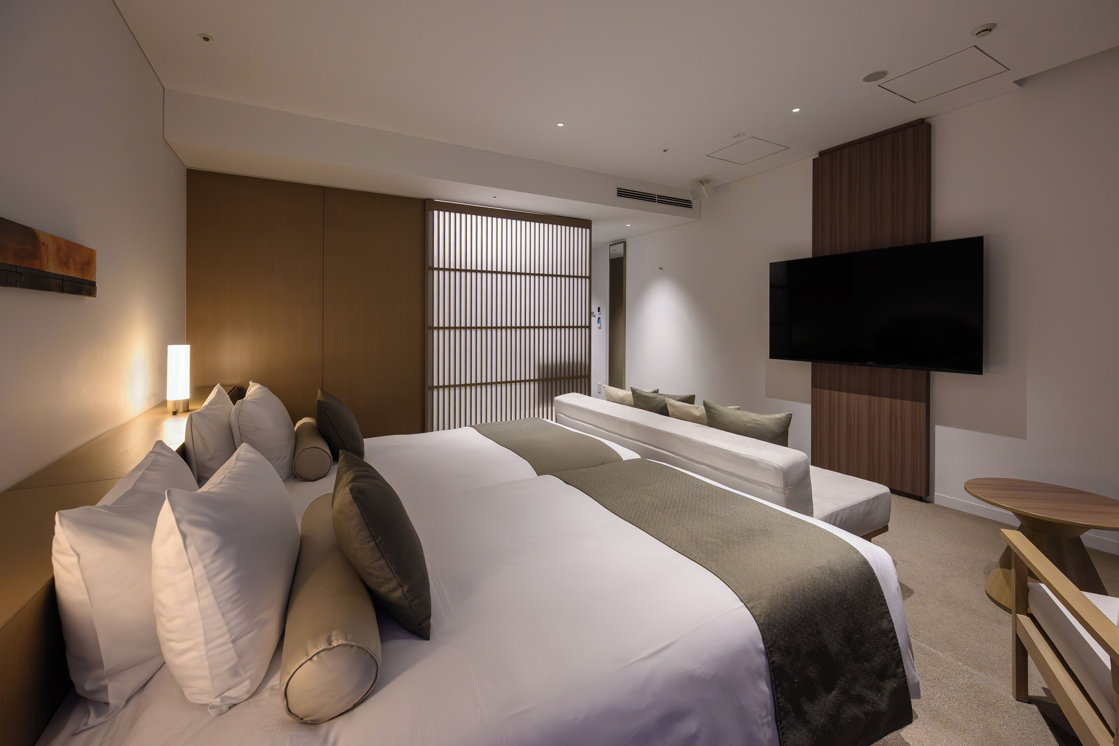 Une chambre d’hôtel moderne dotée d’un grand lit, d’un coin salon, d’une télévision et d’une cloison en bois.