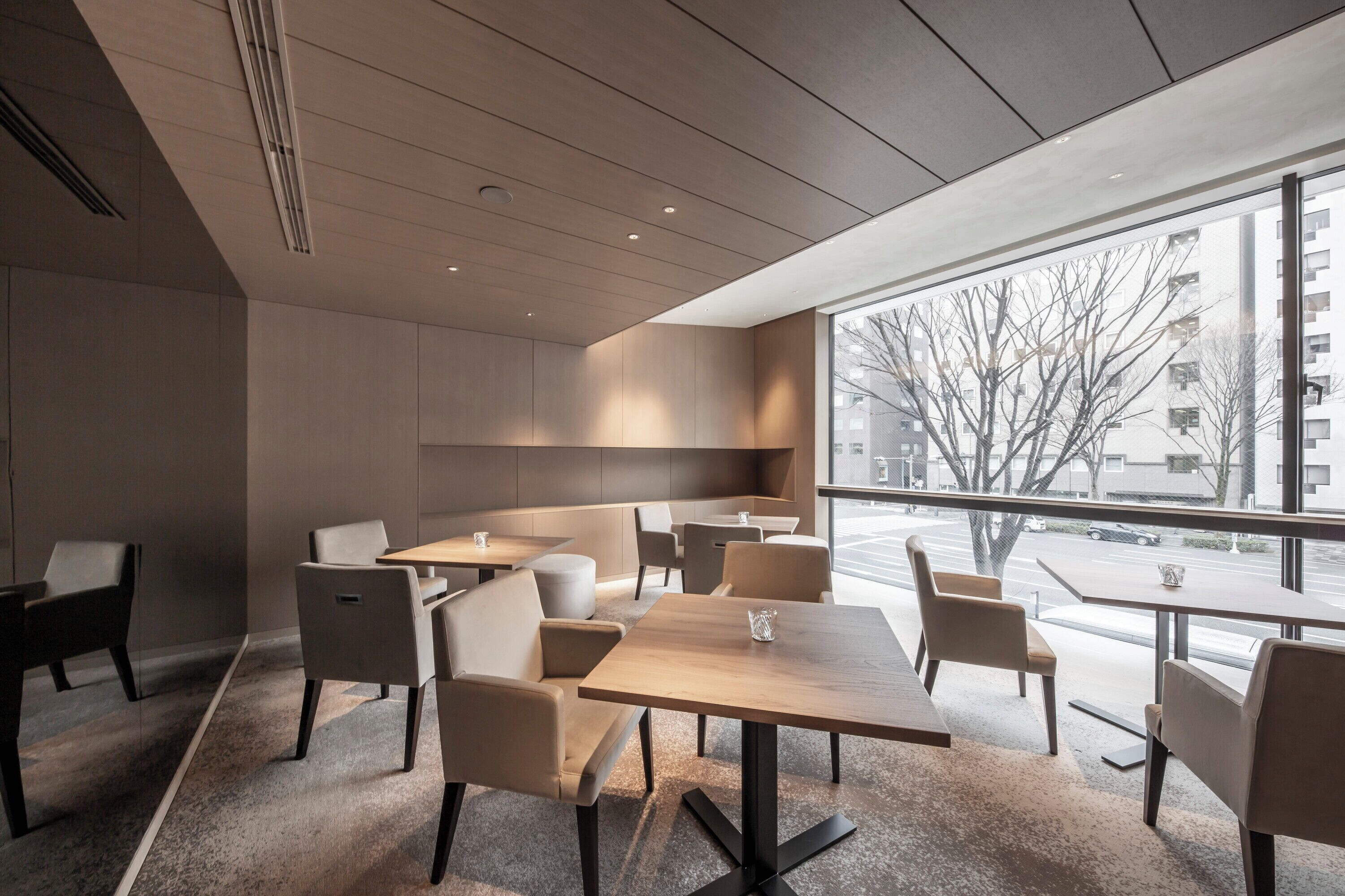 A modern interior with a large window, multiple tables and chairs, and a minimalist design.