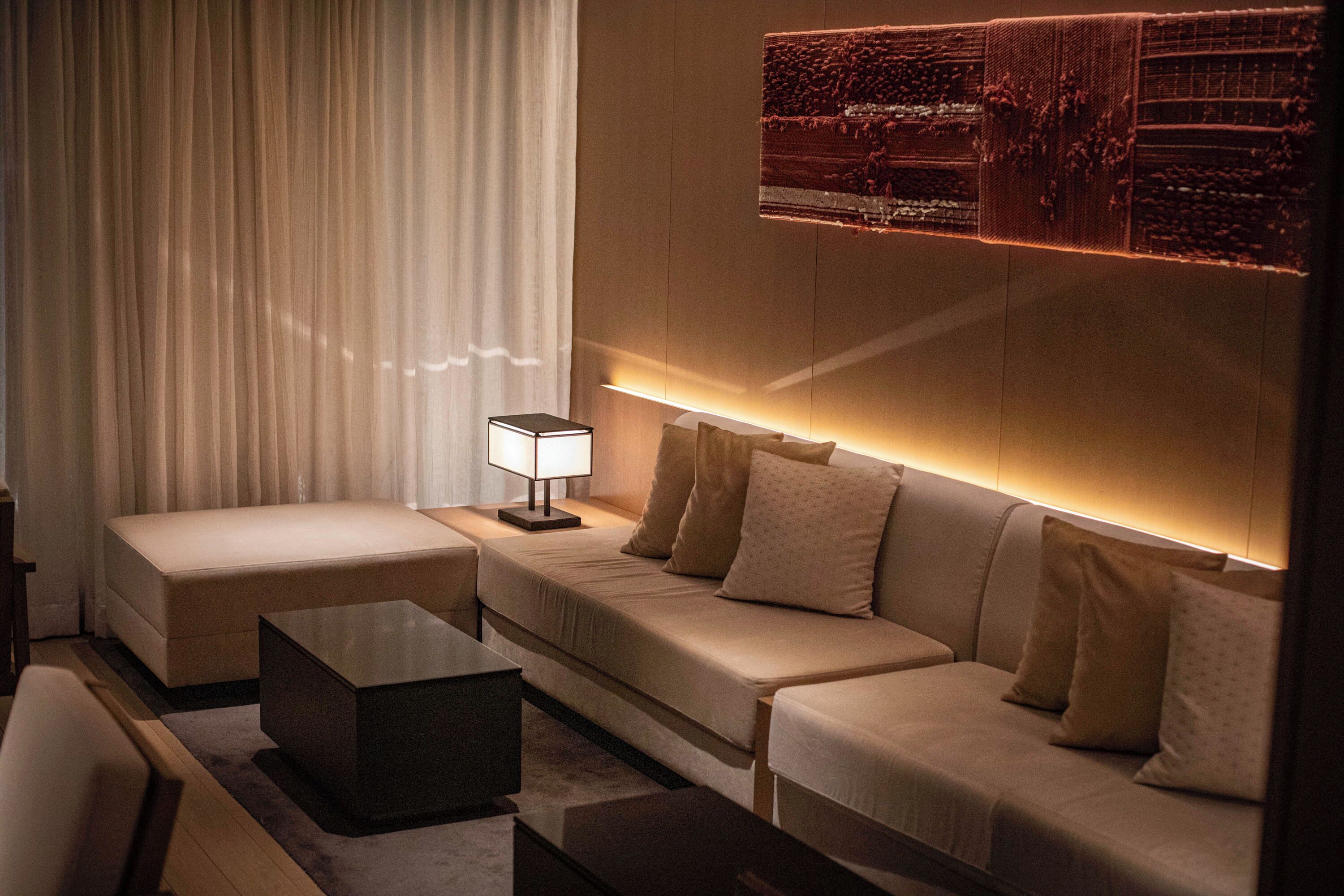 Une chambre d’hôtel moderne avec un canapé, une petite table et une lampe.