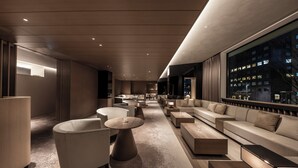 A modern lounge area with sofas, tables, and a large window offering a city view. - The Royal Park Hotel Iconic Kyoto (Kyoto)