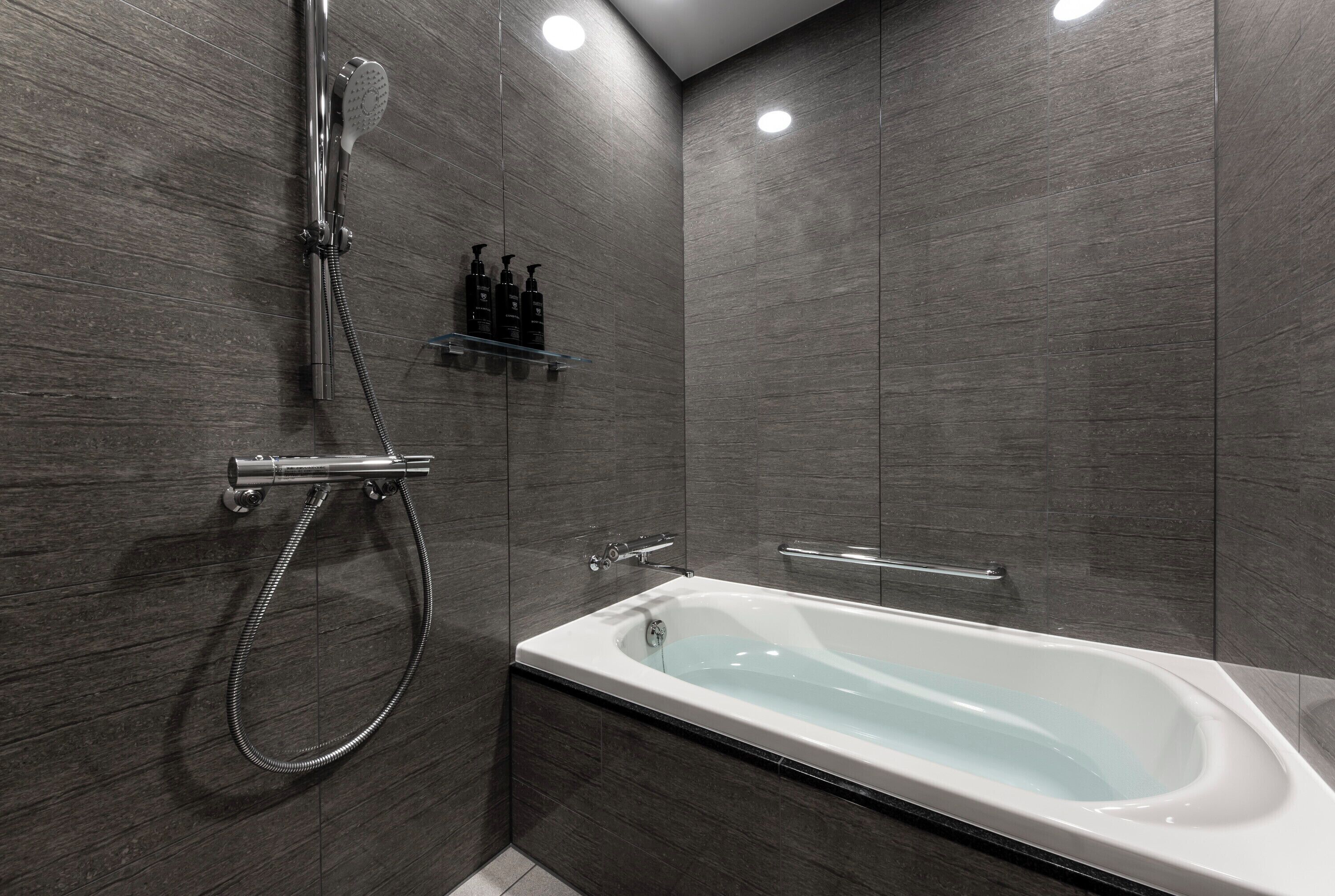 Un baño moderno con bañera, ducha y un estante con artículos de aseo.