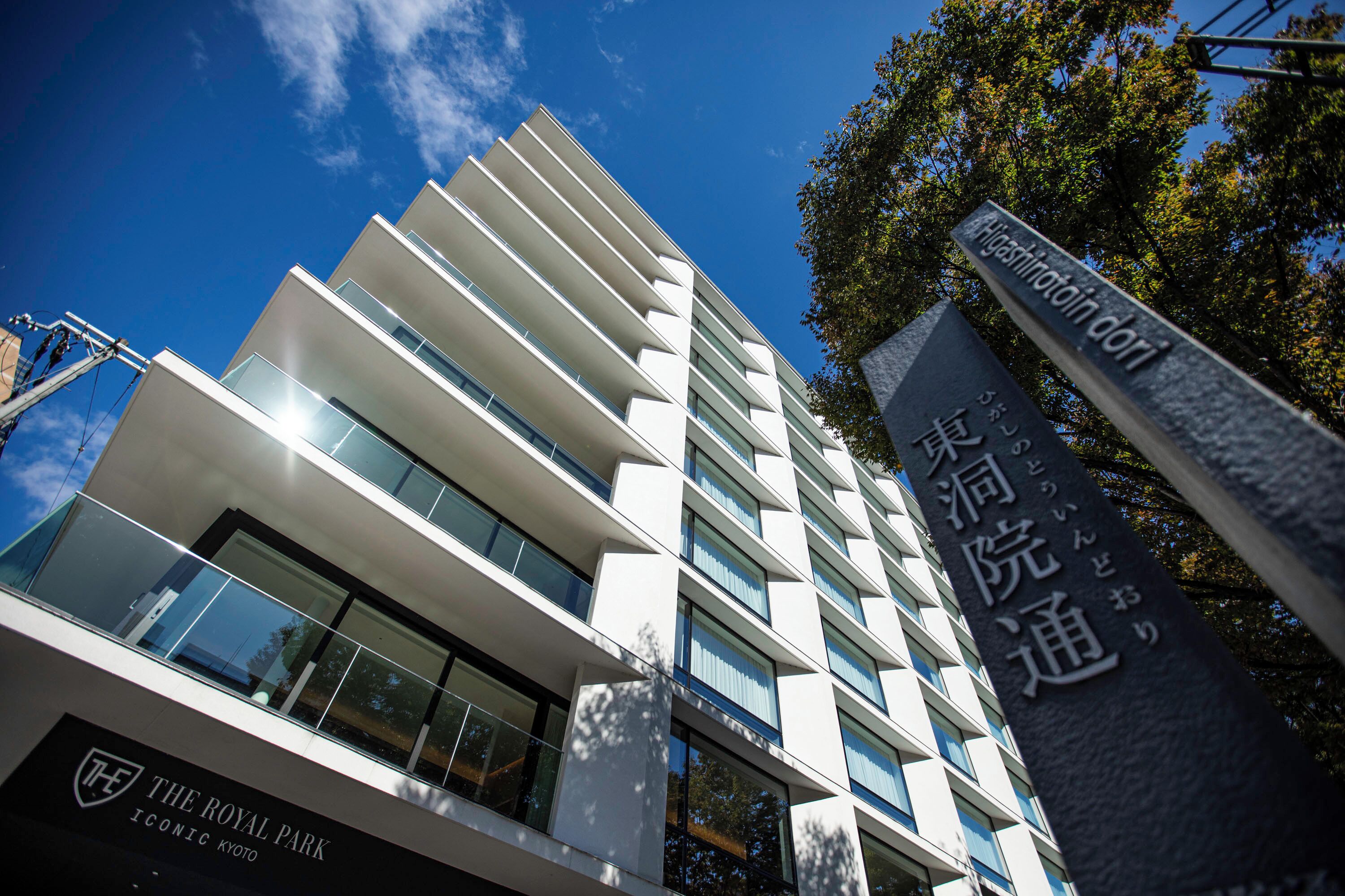A modern building with multiple balconies and large windows, featuring a sign with Japanese characters.