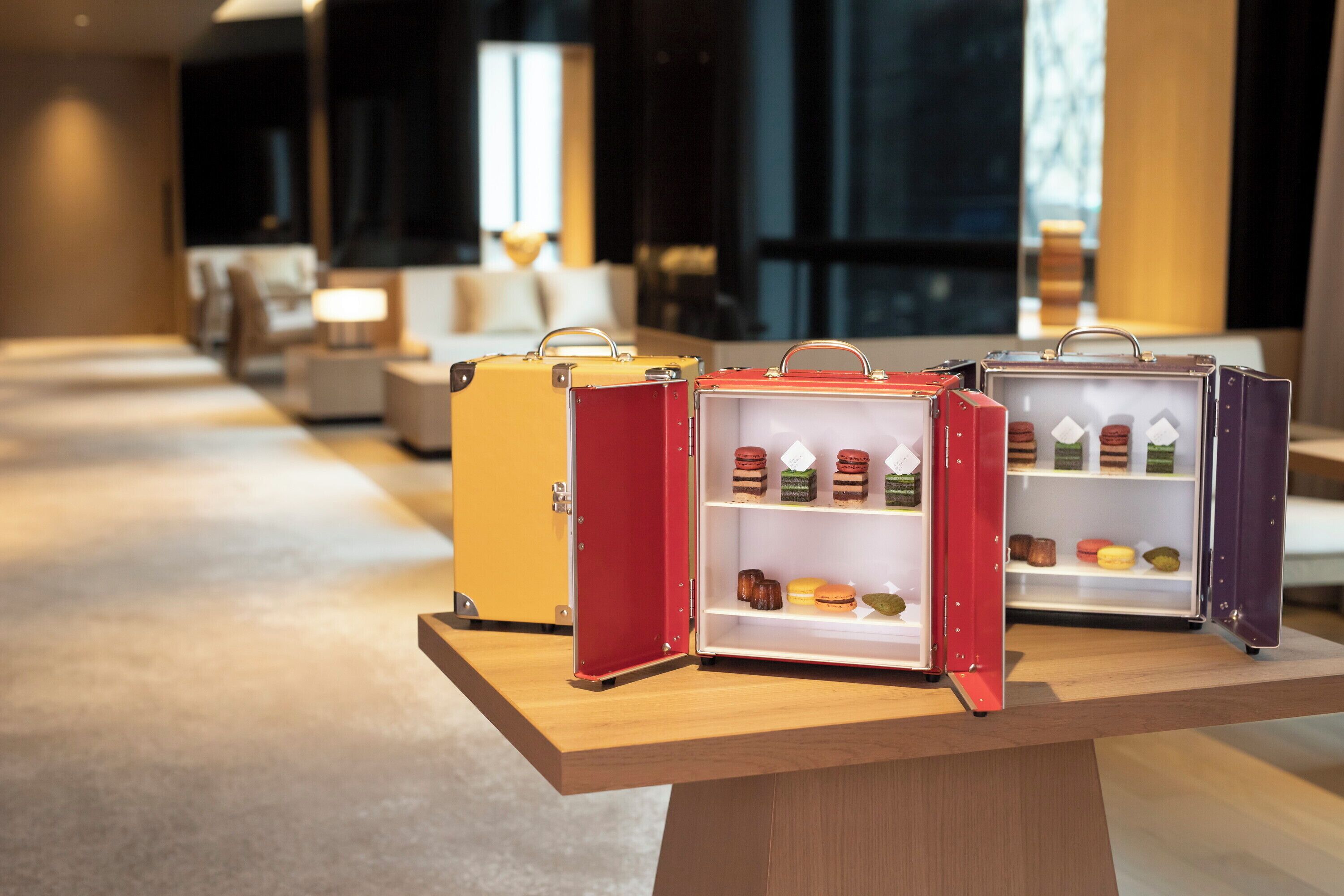 A display of miniature suitcases with compartments containing various food items.