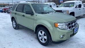 Un SUV verde claro estacionado en un estacionamiento nevado con otros vehículos.